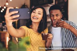 Woman taking selfie with friend making funny expressions while drinking coffee 5zEYP0