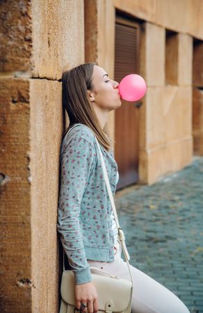 Side view of woman blowing pink bubble gum