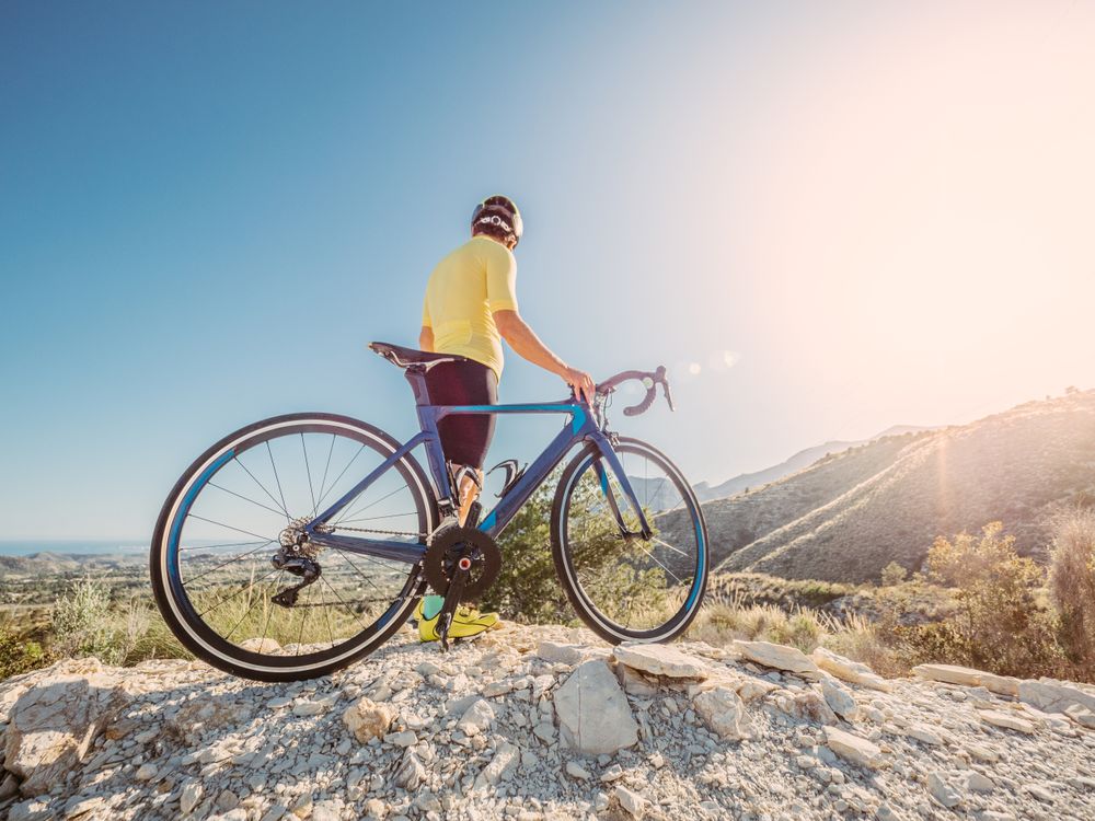 man resting and enjoying the views while riding a bicycle on a mountain road