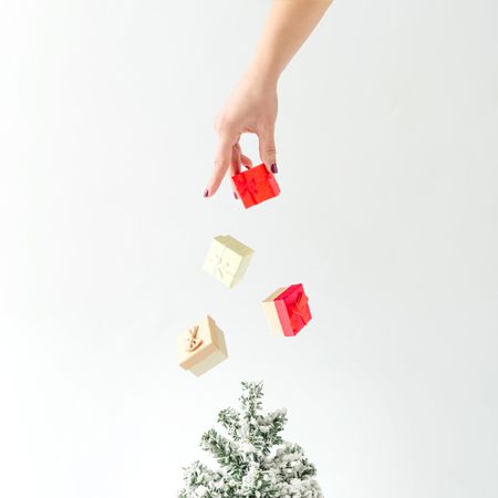 Hand sprinkling gift boxes on tree