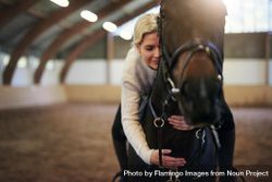 Female horse trainer hugging her horse companion while riding on his back 4dXNL4