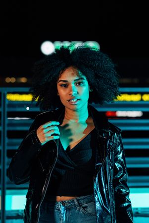 Serious Black woman on a rooftop in blue green light