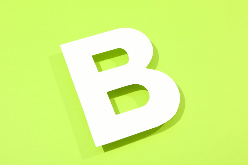 Paper letter B on color background, space for text
