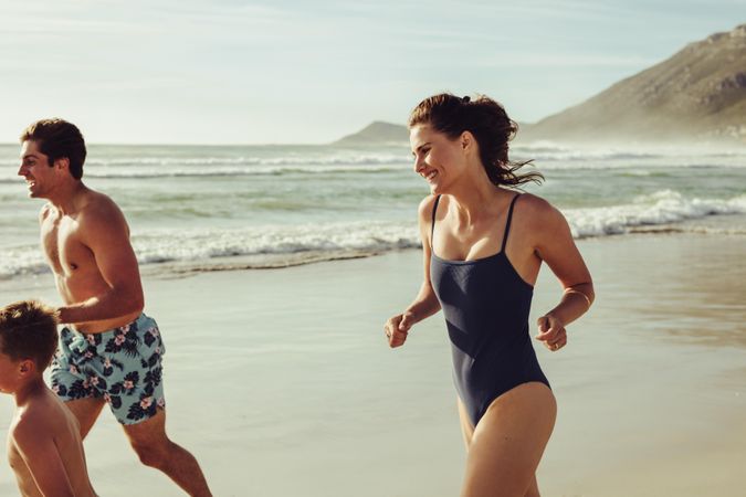 Woman in bikini running with her family on the beach