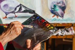 Crop artist with paint palette in workshop