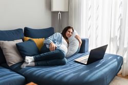 Smiling pregnant woman watching movie on laptop