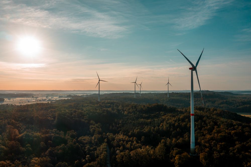 Drone image with wind turbines in the forest at sunrise in Germany