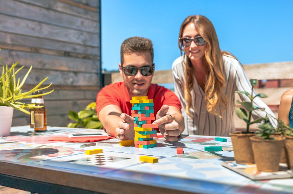 Concentrated young man pushing game piece next to female friend in rooftop party