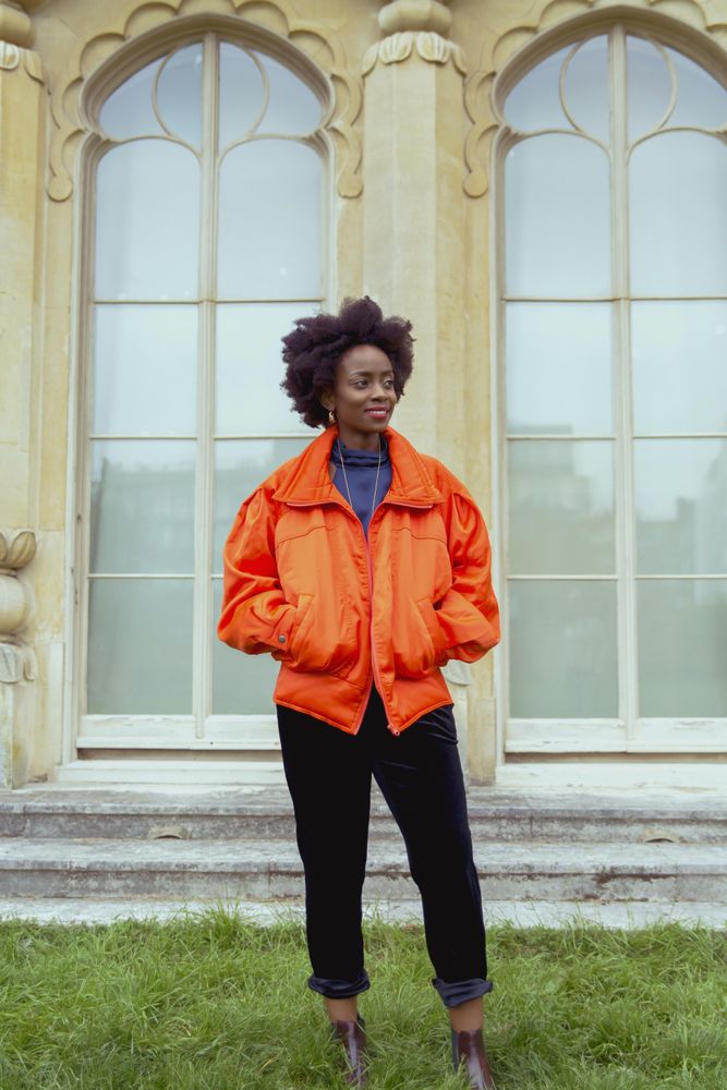 Woman in orange jacket standing on green grass