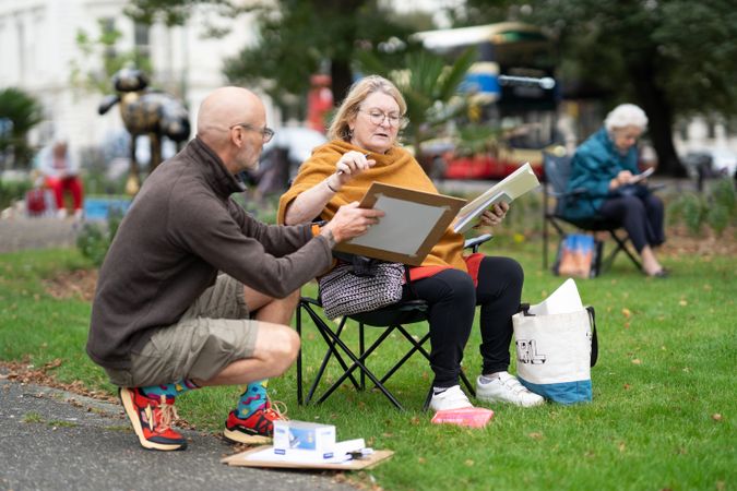 Older woman sitting calmly outside drawing talking to instructor