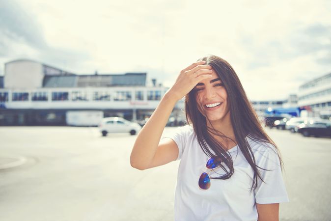 Smiling woman with hand to head on sunny day