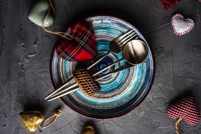 St. Valentine day table setting with colorful blue plates and felt heart ornaments