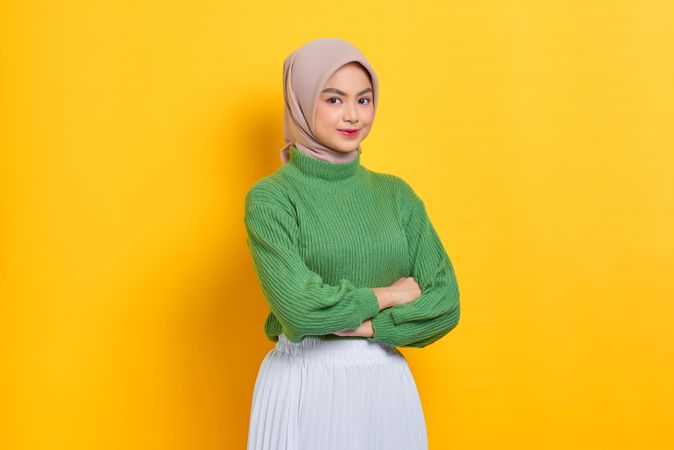 Smiling woman in headscarf turned to the side with arms crossed