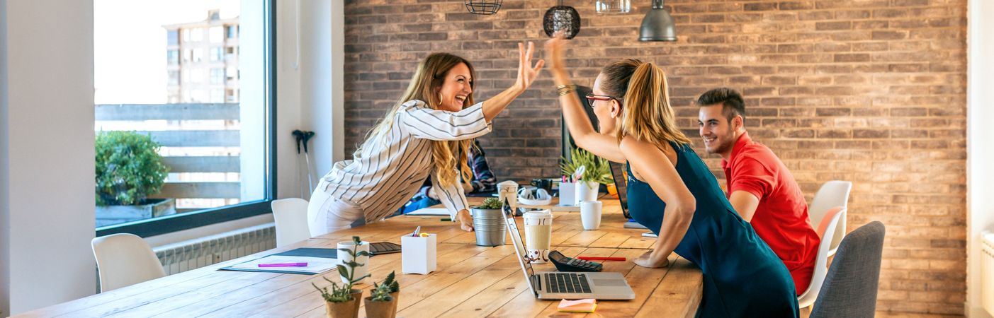 Business women celebrating a success high-fiving in the office