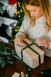 woman wrapping christmas gift at home
