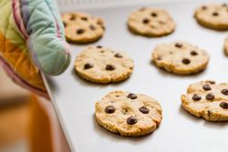 Woman holding a tray with baked cookies with kitchen gloves