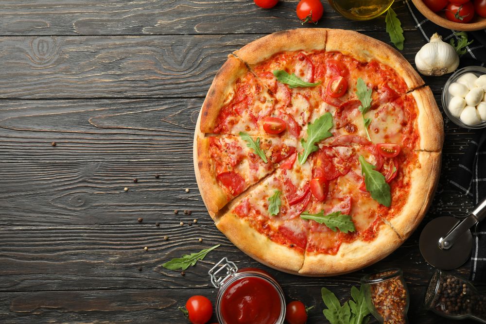 Tasty pizza and ingredients on wooden background