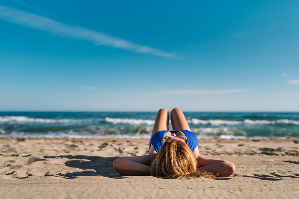 Woman lying down on sandy beach