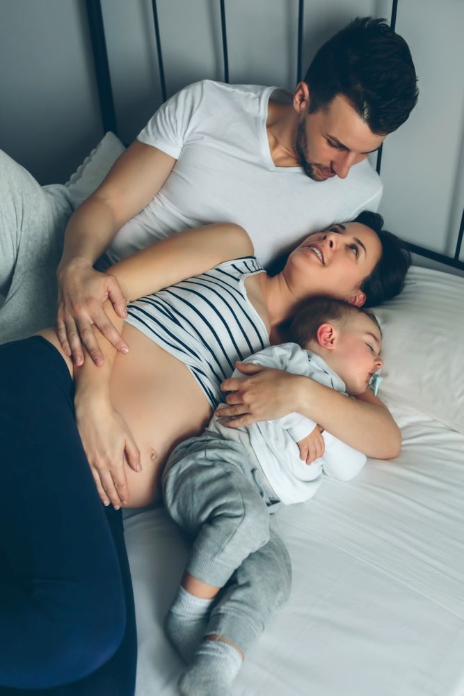 Pregnant woman with man and boy in bed