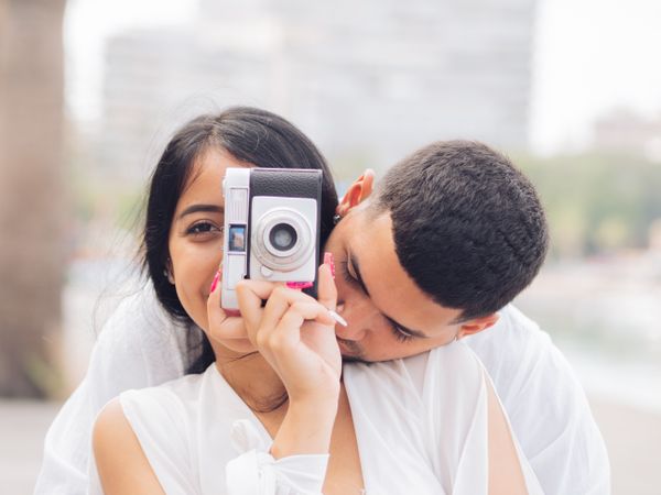 Woman taking photo and sitting with man on bench