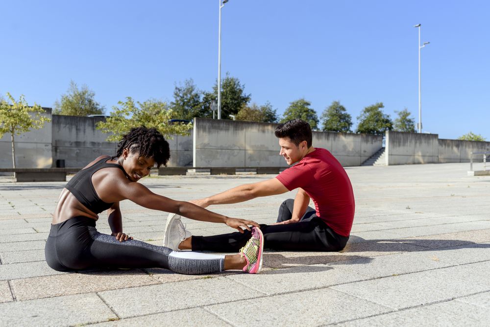 Sportive couple doing stretch exercises in city
