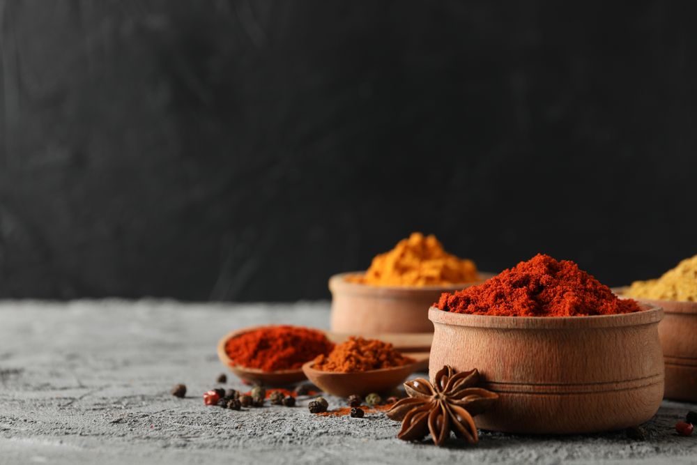 Side view of bowls of spices and garlic bulb, copy space