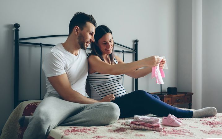 Man and pregnant woman looking baby clothes