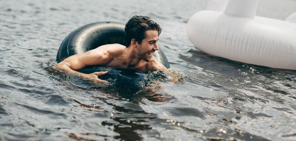 Man using a inflatable rubber tube to swim in a lake