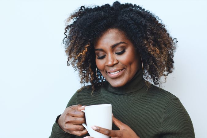 Black woman looking at cup of coffee