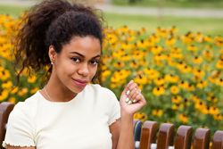 Black female sitting on bench in front of flowers