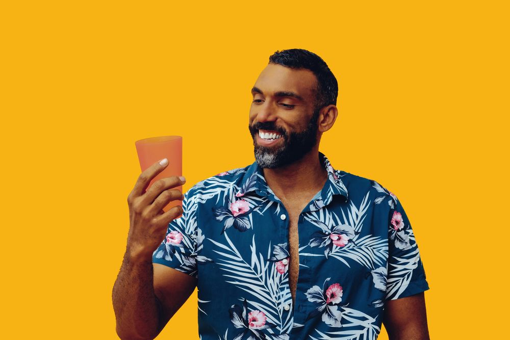 Male smiling at his refreshing drink in a orange cup with copy space