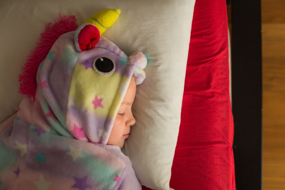 Girl in unicorn pajama sleeping in bed