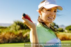 Happy female golfer holding golf clubs behind neck 5RaBr0