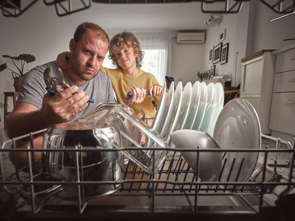 Serious man and son near broken dishwasher