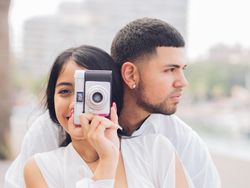 Woman taking photo and sitting with man on bench