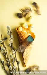 Waffle cone with small speckled eggs and pussy willow on yellow pastel background 5kRjvQ