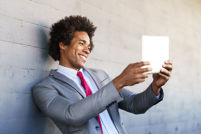 Man chatting on a tablet leaning on wall