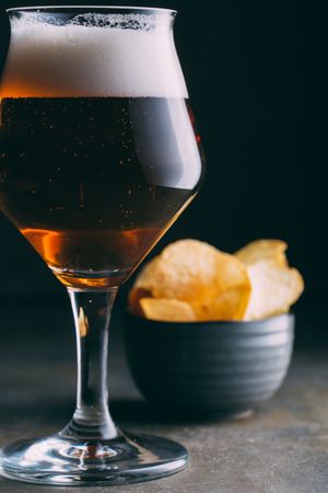 Glass of beer and chips on dark and grunge background