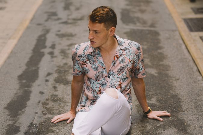 Handsome man sitting on asphalt
