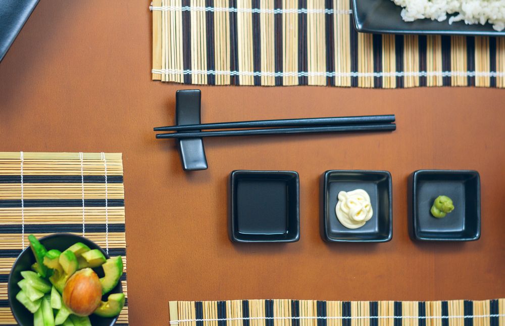 Top view of saucers with wasabi, mayonnaise and soy sauce ready to eat sushi