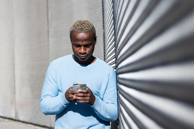 Young Black guy browsing smartphone on street