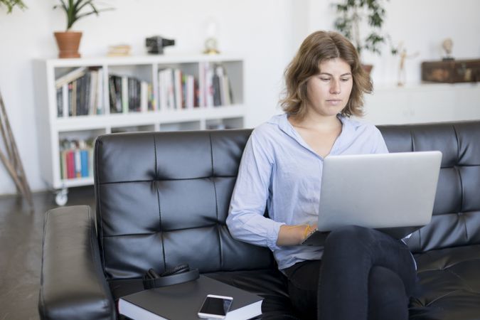 Woman sitting on a sofa at home working on a laptop