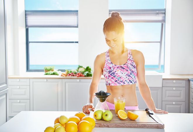Woman looking down at cutting board with juice, apples and oranges