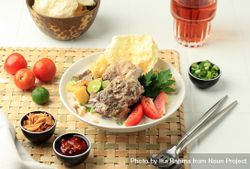 Soto betawi, bowl of Indonesian beef stew served on bamboo placemat 4MVLrb