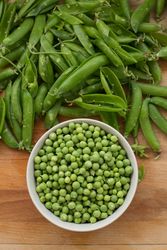 Fresh peas and pea pods on wooden background