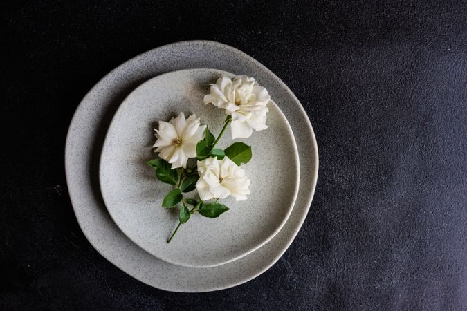 Top view of minimalistic table setting with flowers on grey plate with copy space