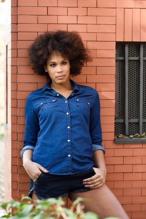 Female relaxing on building with hands in her pocket