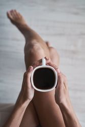 Faceless woman sitting with coffee cup in hands