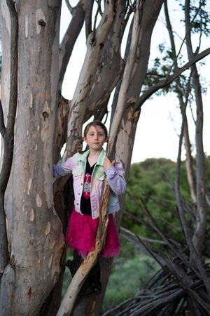 Confident little girl standing in eucalyptus tree after climbing