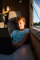 Boy watching film on laptop in van